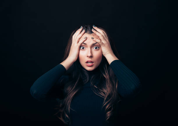istock Shocked stressed woman touching head in panic attack isolated on black background 1138637881