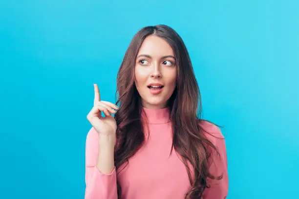 Photo of Young beautiful woman having good idea with her finger pointing up isolated on blue background