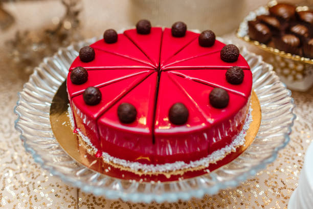 istock cake in red glaze on table, cut into pieces. decorated with chocolate balls. candy bar 1138639803