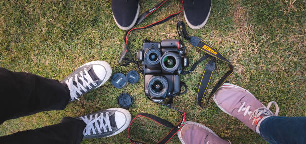 drei dslrs der marke nikon und canon hielten sich auf grünem gras. diese beiden sind die am weitesten verbreiteten und vertrauenswürdigsten unternehmen in bezug auf dslrs. - delhi new delhi panoramic india stock-fotos und bilder