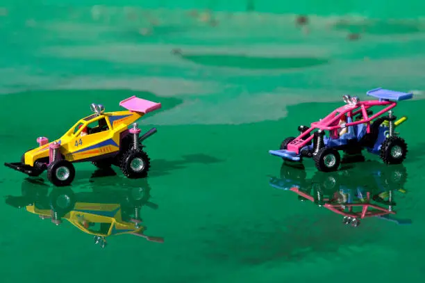 Plastic off-road toy car, green cement floor, water