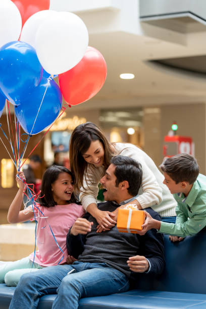 família feliz no shopping que dá um presente ao pai - men giving balloon women - fotografias e filmes do acervo