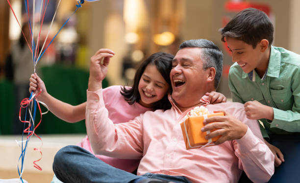 Very happy grandfather celebrating Father's Day with his grandchildren Portrait of a very happy grandfather celebrating Father's Day with his grandchildren and getting a present - lifestyle concepts father son grandfather fathers day stock pictures, royalty-free photos & images