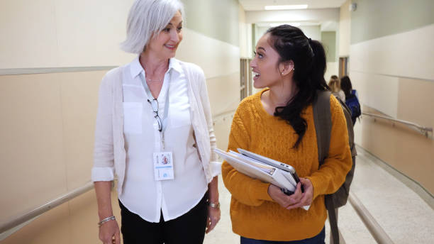 high school student and teacher walk down hallway together - volunteer senior adult teenager occupation imagens e fotografias de stock