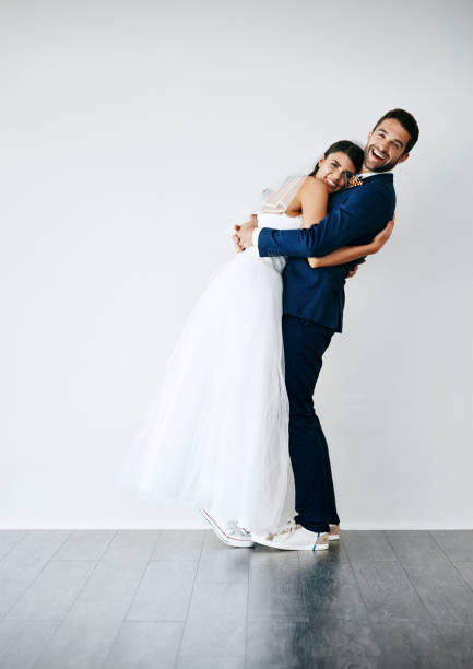Studio shot of a newlywed couple standing against a gray background