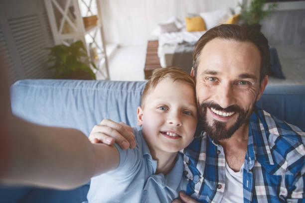 istock Glad dad and positive kid taking selfie 1138645231