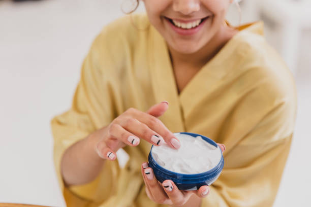 istock Cute girl is getting ready to start her day. She uses a moisturizer on her face. During this she has a towel on her head. 1138647973
