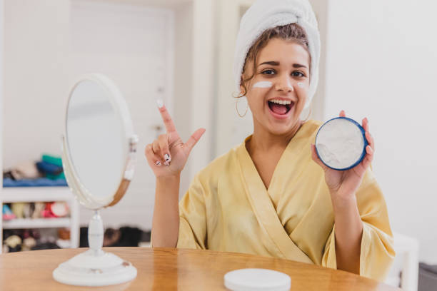 istock Cute girl is getting ready to start her day. She uses a moisturizer on her face. During this she has a towel on her head. 1138648108