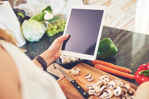 Cropped shot of an unrecognizable woman using a digital tablet while cooking