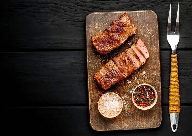 istock Beef steak on the cutting board with spices, wooden dark table,Top view with copy space. 1138650342