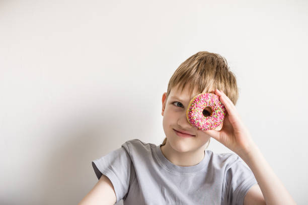 istock Teen boy looks into glazed donut, copy space 1138652402