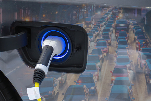 Electric vehicle , Smart car , Air pollution and reduce greenhouse gas emissions concept. Double exposure of charging Electric car with power cable supply plugged in and city night light view.