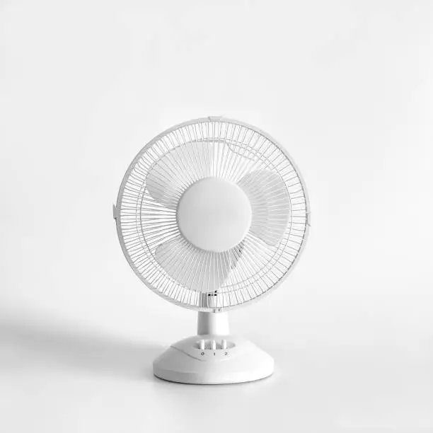 White desktop electric fan on light white background. Minimal concept.