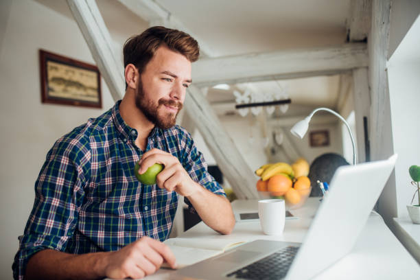 istock Man holding an apple and looking at laptop 1138653667