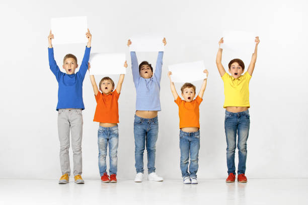 Group of children with a white banners isolated in white Group of surprised children with a white empty banners isolated in light studio background. Education and advertising concept blackboard child shock screaming stock pictures, royalty-free photos & images