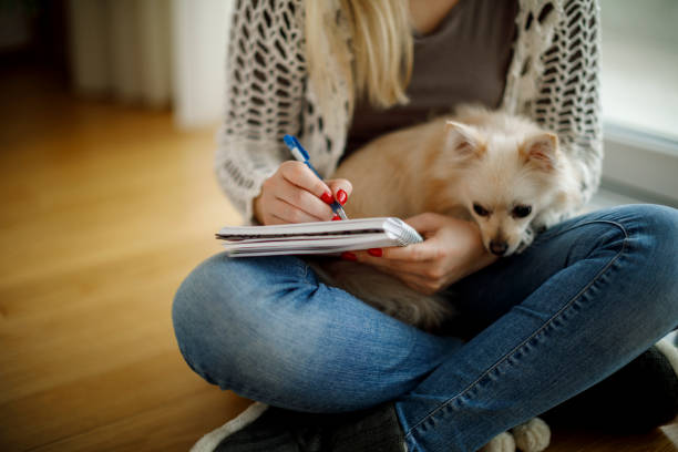 istock Young woman with dog sitting on the floor and writing notes 1138653889