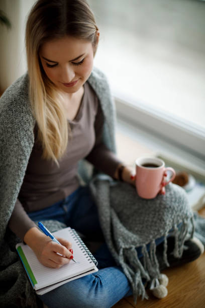 istock Young woman sitting on the floor and writing notes 1138653893