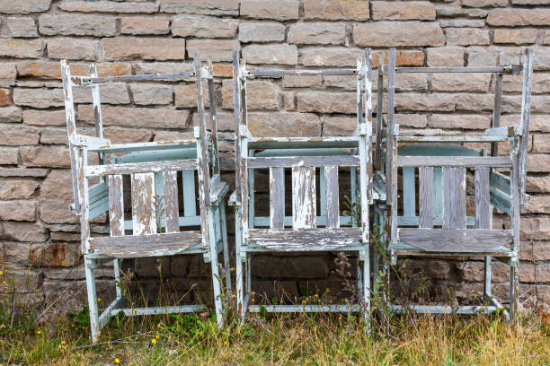 istock Old leftover garden chairs stacked on a wall in a backyard 1138654715