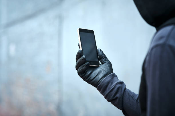 Having a quick look at where I'll strike next Shot of a male burglar using his phone outdoors conspiracy stock pictures, royalty-free photos & images