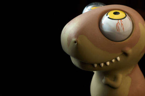 istock toy dinosaur with a huge dobrymi eyes on a black background looks up. Request. 1138655364