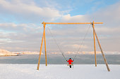 Asian woman sitting on huge swing on Arctic beach