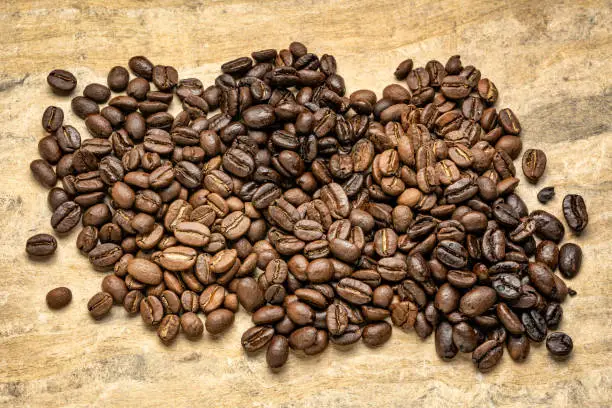 sampler of coffee beans from different parts of the world - overhead view against handmade textured paper