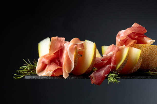 istock Prosciutto with melon and rosemary  on a black background. 1138664601