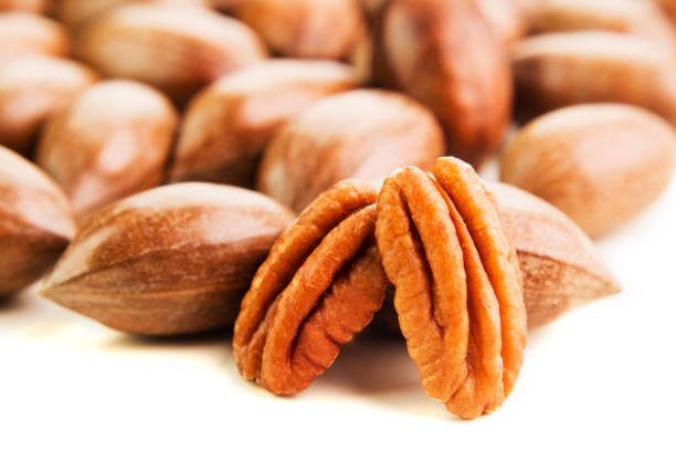 istock Not cleaned pecan nuts in the shell isolated on white. 1138665189