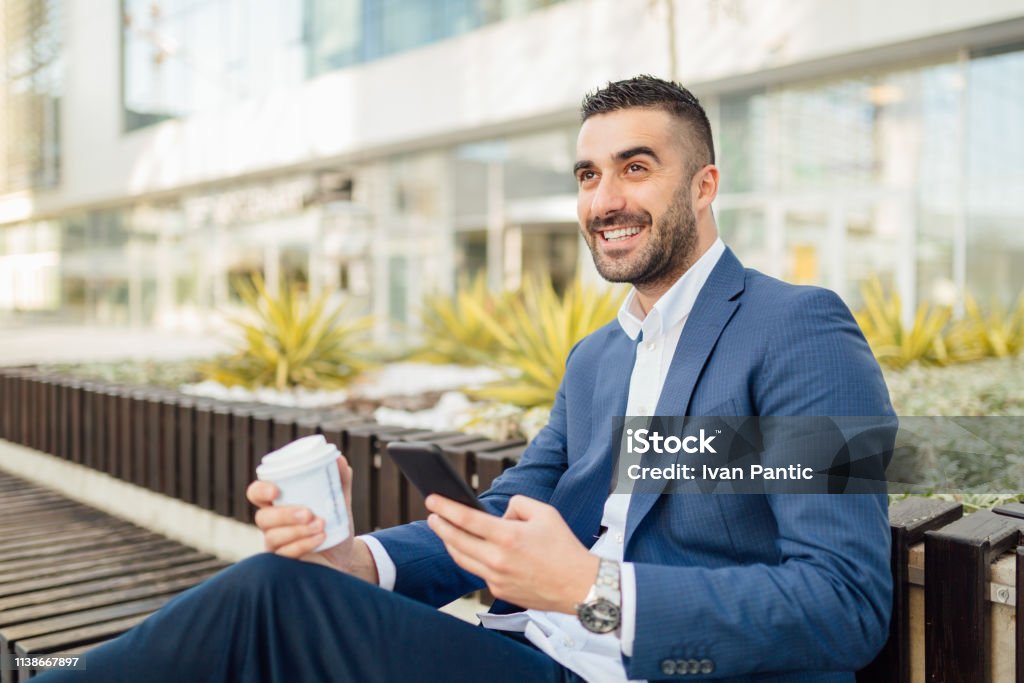 Handsome businessman working on the go Businessman smiling and taking a short break from work for a cup of coffee. Adult Stock Photo