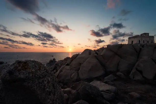 rocky coast seascape, sunset sun shines orange in the blue sky with few clouds, relaxing feeling of peace and tranquility, Capo Testa, Santa Teresa di Gallura, Olbia Tempio, Sardinia, Italy