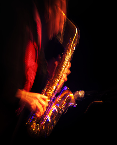 Jazz music concept. Saxophone player performing on stage. Sax player going crazy. Abstract motion blurred image.