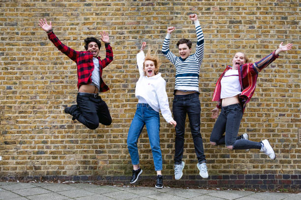 Group of teenagers jumping agains a brick wall Group of teenagers jumping agains a brick wall jumping teenager fun group of people stock pictures, royalty-free photos & images
