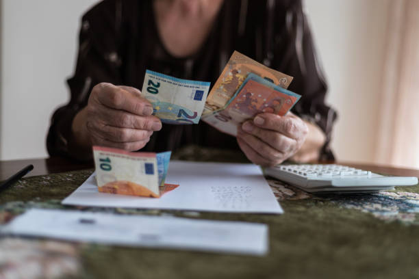 mani di un uomo anziano che tiene banconote in euro. concetto di pensionati in difficoltà. - pension foto e immagini stock