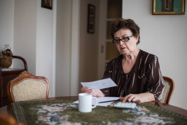 femme âgée intéressée examinant les finances intérieures. - women poverty senior adult mature adult photos et images de collection