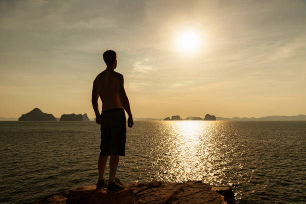 Man's silhouette on cliff at sunset, Andaman sea