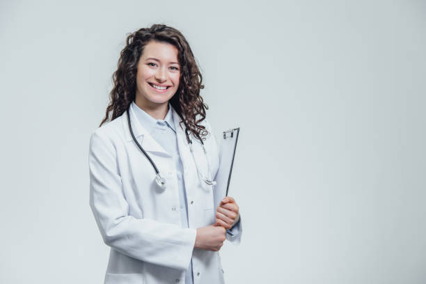 istock Happy young woman doctor. During this, holds a black folder with documents, has a friendly expression. Going to look at the patient. Gives a few tips, isolated on a gray background. The concept of medicine. 1138674558