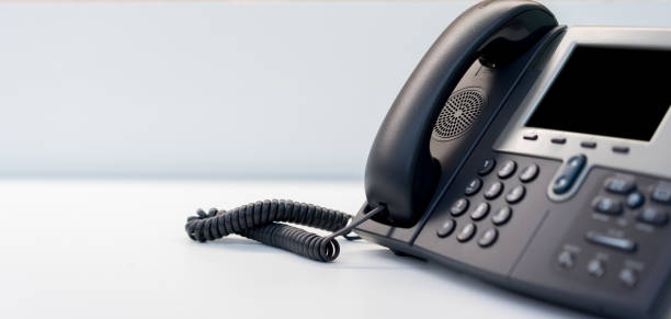 feche acima da tecnologia do telefone voip que está na mesa do escritório na sala de escritório para o conceito do trabalho do centro da operação da rede - responder - fotografias e filmes do acervo