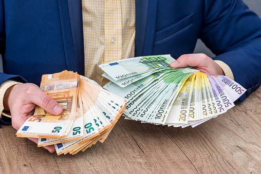 Business person placing euro banknotes into fan
