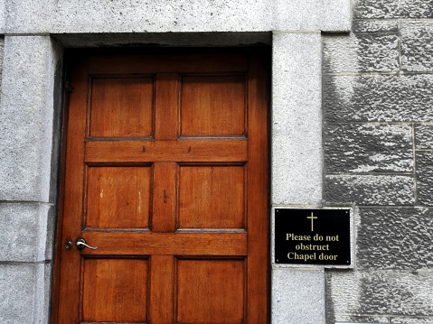 27th March 2019, Dublin, Ireland. A 'Please do not obstruct chapel door' wall sign beside church door entrance on North Circular Road.