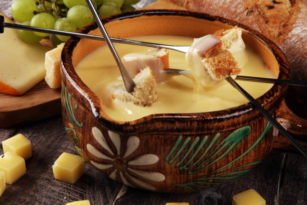 istock Gourmet Swiss fondue dinner on a winter evening with assorted cheeses on a board alongside a heated pot of cheese fondue with two forks dipping 1138694280
