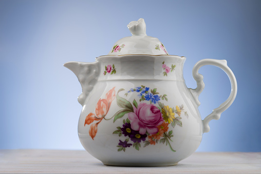 Porcelain teapot isolated on a blue background.