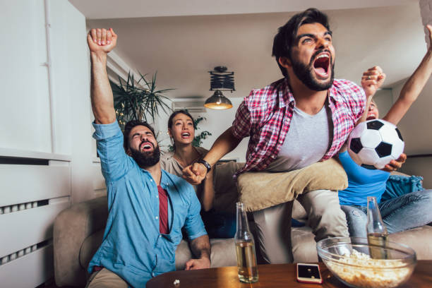 amigos felizes ou ventiladores de futebol que prestam atenção ao futebol na tevê e que comemoram a vitória em casa. conceito da amizade, do esporte e do entretenimento. - men home interior house entertainment - fotografias e filmes do acervo