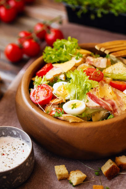 istock Caesar salad with cherry tomatoes and quail eggs in a wooden bowl 1138697957
