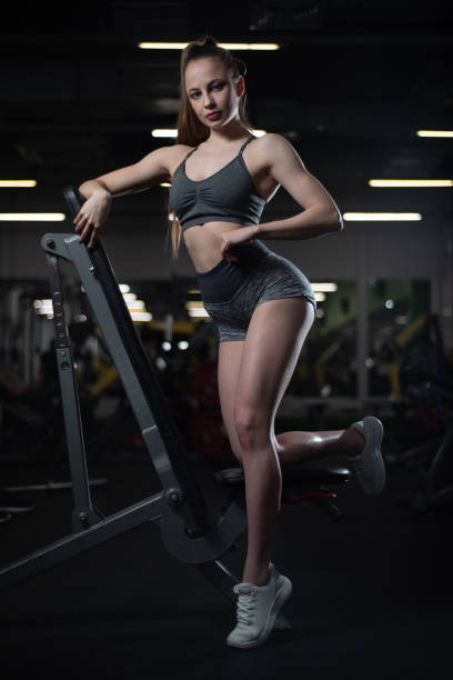 fille de remise en forme posant dans la salle de gym sur le banc montrant son corps - showing off muscular build the human body human muscle photos et images de collection
