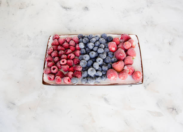 istock Frozen berries on a white marble table. Strawberries, blueberries, raspberries on a plate close-up. 1138698967