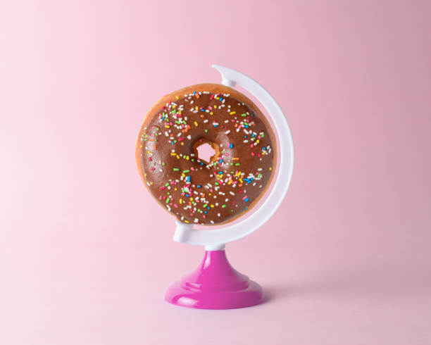 istock Donut on a globe stand on pastel pink background. Minimal concept. 1138701781