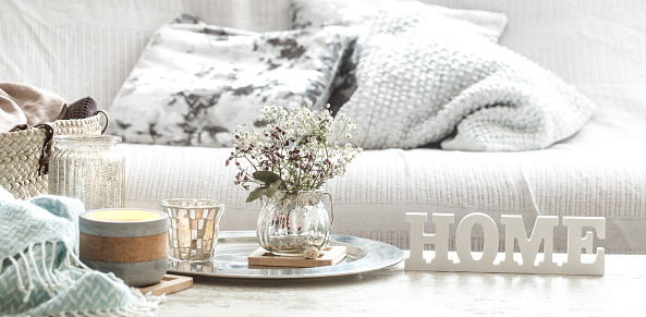 Home decorations in the interior of a letter with an inscription home on a wooden background in the interior of the bedroom with turquoise blanket