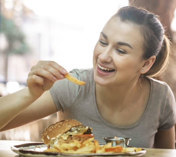istock Young woman in cafe eats appetizing sandwich 1138709676