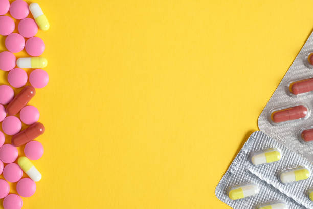 istock Pink pills with capsules on a yellow background. Top view. Copy space. Left and right side. 1138709896