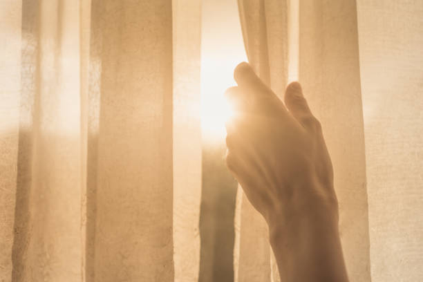 la mano de la mujer abre las cortinas en el dormitorio - window sun sunlight vertical fotografías e imágenes de stock